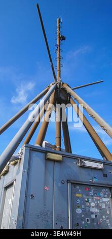 Une antenne métallique s’élève contre un ciel bleu, entourée d’équipements techniques, représentant une infrastructure de communication en milieu industriel. Banque D'Images