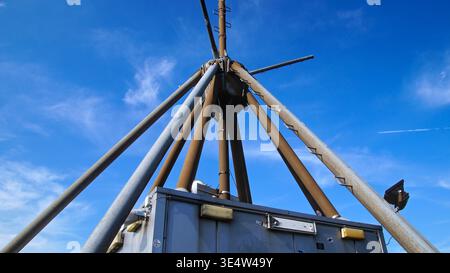 Une antenne métallique s’élève contre un ciel bleu, entourée d’équipements techniques, représentant une infrastructure de communication en milieu industriel. Banque D'Images
