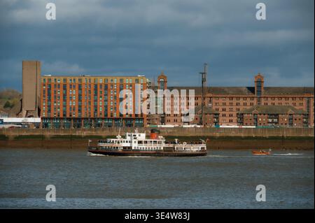 Un ferry et un bateau de sauvetage voyagent sur la rivière Mersey à Liverpool, avec le bâtiment Tobacco Warehouse en arrière-plan. Banque D'Images