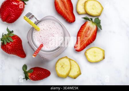 Nourriture, Smoothie ou cocktail milkshake à base de fraises fraîches, banane, yaourt ou lait et glaçons dans un pot Mason sur une table en marbre. Concept de HEA Banque D'Images