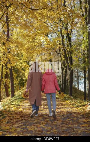 Nourriture, Une promenade dans le parc d'automne. Maman et fille marchent avec des bouquets de feuilles d'érable. Mise au point sélective Banque D'Images