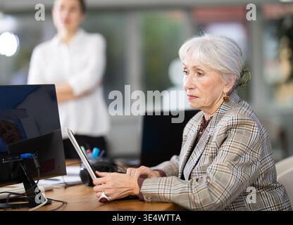 Femme mature travaillant sur ordinateur dans le bureau moderne Banque D'Images