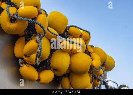 Bouées de pêche jaune vif et flotteurs suspendus sur un bateau commercial sous Blue Sky Banque D'Images