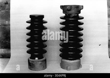 Sloviansk, 1950s-1960s, armature-Insulator Plant (AIZ). Une vue d'archives comparatives montrant deux isolateurs électriques en céramique multi-nervurée finis de différentes tailles. Recouverts d'une glaçure brun foncé brillante et équipés de matériel métallique industriel lourd, ils se tiennent sur un fond Uni. Cette photographie détaillée du produit met en évidence les normes d'ingénierie de haute qualité et la production diversifiée du secteur soviétique de la fabrication d'équipements électriques, préservant le patrimoine industriel du Donbass paisible. Banque D'Images
