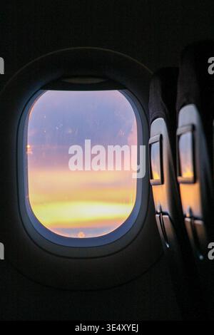 Le point de vue du passager d'un avion depuis un siège côté fenêtre montrant un coucher de soleil vibrant sur l'horizon, capturant l'essence du voyage mondial, voyage, et f Banque D'Images