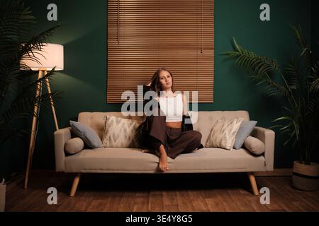 Jeune femme se relaxant sur le canapé dans le salon moderne Banque D'Images