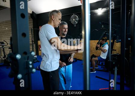Entraîneur entraîneur homme sur la machine d'exercice au gymnase Banque D'Images