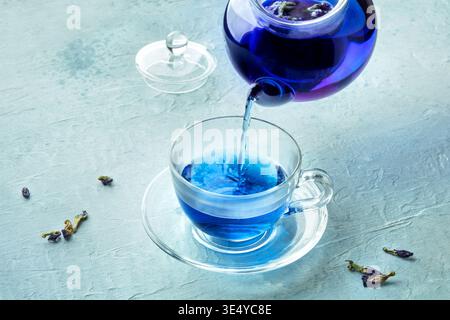 Thé bleu, une infusion de fleurs de pois papillon, versé dans une tasse à partir d'une théière Banque D'Images