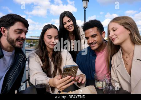 Des amis divers partageant du contenu sur un téléphone mobile Banque D'Images