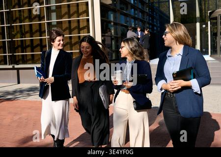 Des collègues femmes d'affaires marchant parlant en riant à l'extérieur du quartier des affaires Banque D'Images