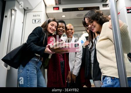 Divers amis prenant selfie ensemble sur le train de métro en mouvement Banque D'Images