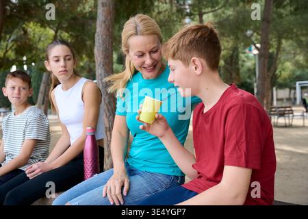 Mère et trois enfants se relaxant ensemble dans le parc Banque D'Images