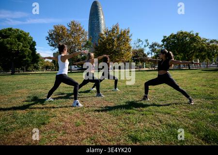 Les femmes pratiquant le yoga guerrier posent dans le parc de barcelone Banque D'Images