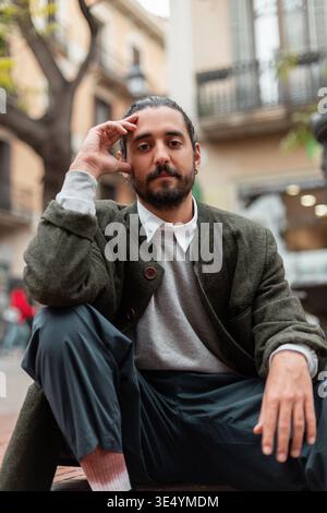 Mode élégant homme à la mode dans une tenue élégante avec manteau se trouve dans la rue de la ville de Barcelone Banque D'Images