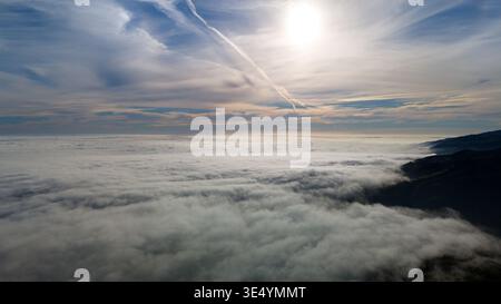Vue aérienne d'une mer de nuages roulant sur les collines sombres sous un soleil éclatant et un ciel bleu, Malibu, Californie, États-Unis. Banque D'Images