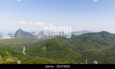 Vue aérienne des collines verdoyantes et karsts calcaires s'élevant de la mer sous un ciel bleu clair à Phang Nga, Thaïlande. Banque D'Images