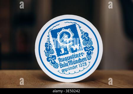 Nice, France - 8 mai 2025 : montagnes russes Augustiner Brau Munchen avec logo bleu vintage de brasserie et design bavarois traditionnel sur abeille en carton rond Banque D'Images