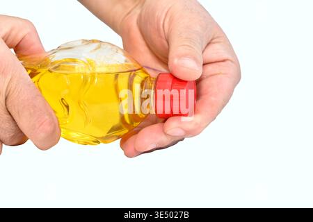 Une bouteille d'huile végétale. Un homme ouvre une bouteille d'huile. Banque D'Images