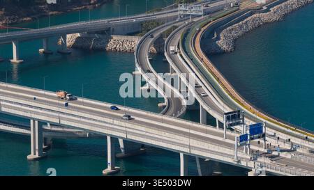 Vue aérienne du pont Cross Bay Link avec des rampes d'accès incurvées et des véhicules au-dessus de l'eau turquoise dans les nouveaux Territoires, Hong Kong. Banque D'Images