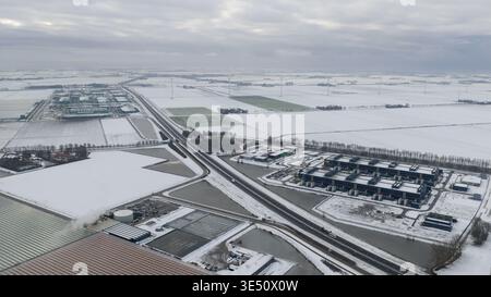 Vue aérienne du centre de données Agriport A7 entouré de champs enneigés et de serres sous un ciel nuageux hivernal à Middenmeer, Noord-Hol Banque D'Images