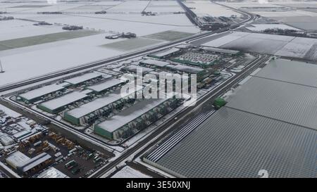 Vue aérienne du centre de données Agriport a7 et des grandes serres entourées de champs enneigés à Middenmeer, Noord-Holland, pays-Bas. Banque D'Images