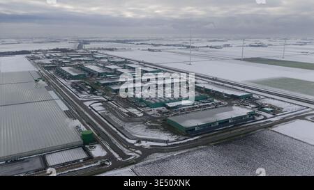 Vue aérienne du centre de données Agriport a7 avec bâtiments industriels et éoliennes dans un paysage enneigé à Middenmeer, Noord-Holland Banque D'Images