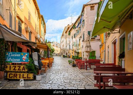 Une rue pavée pittoresque avec des cafés et des boutiques sur le trottoir dans la vieille ville historique de Rovinj, en Croatie, une ville balnéaire dans la région d'Istrie. Banque D'Images