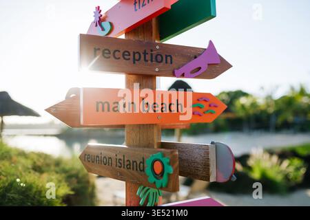 Panneaux de direction en bois coloré pointant vers la plage et la réception dans le complexe tropical. Banque D'Images