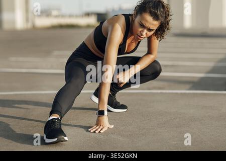 Sportive musclée assise à l'extérieur, se reposant pendant l'entraînement et détournant le regard Banque D'Images