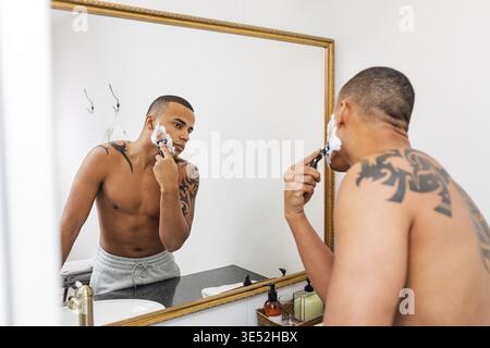 Homme debout devant un miroir rasage après une douche Banque D'Images