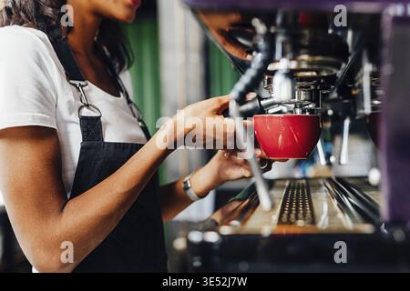 Femelle à l'aide d'un barista méconnaissable cafetière pour préparer un espresso Banque D'Images