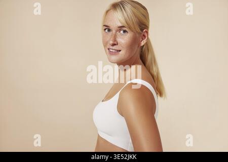 Belle femme blonde avec des taches de rousseur posant en studio sur fond pastel Banque D'Images