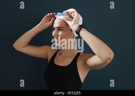 Portrait d'une jeune nageuse portant des lunettes debout sur un fond bleu Banque D'Images