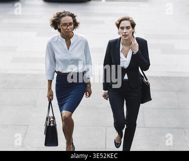 Deux femmes dans le renforcement de l'usure de bureau dans les escaliers dans la ville Banque D'Images