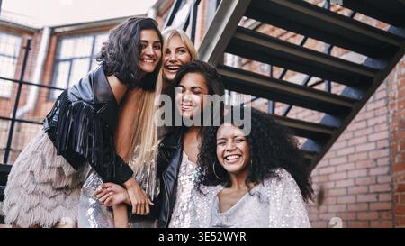 Groupe multiethnique d'amies rire à l'extérieur debout sur l'escalier Banque D'Images