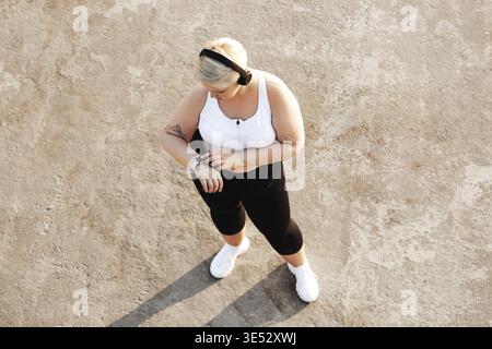 Prise de vue d'en haut d'une jeune femme avec un tracker d'activité de contrôle de corps de taille plus Banque D'Images