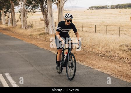 Jeune cycliste professionnel à vélo sur le paysage de campagne. Faites du cyclisme sportif en plein air Banque D'Images