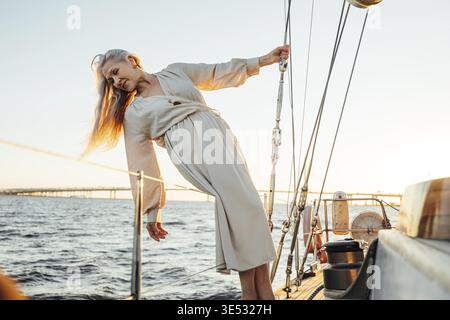 Belle femme âgée avec de longs cheveux posant sur le yacht et vue sur l'eau Banque D'Images