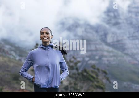 Portrait d'une jeune femme souriante marchant contre une vue imprenable, relaxant après l'entraînement Banque D'Images