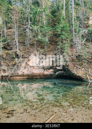 Scène boisée sereine avec une source cristalline, une formation de grottes rocheuses et des reflets calmes. Idéal pour les thèmes de la nature, la tranquillité, la pureté, un Banque D'Images