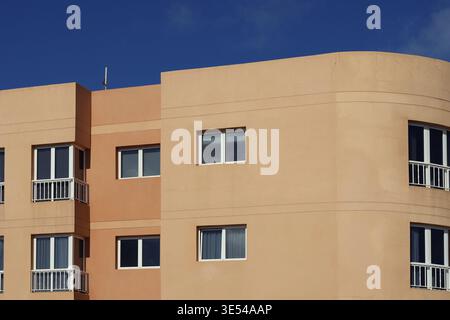 Bâtiment moderne orange avec fenêtres blanches sous un ciel bleu foncé Banque D'Images