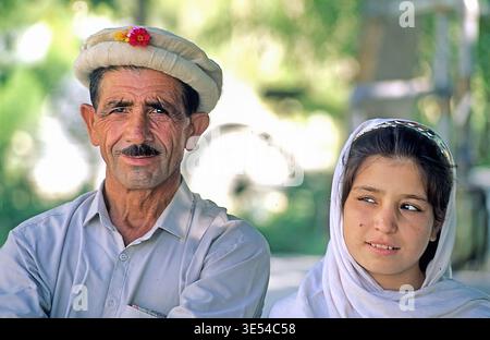 Un père et une fille sont assis ensemble à Lahore, au Pakistan. Ils profitent de leur temps sous le soleil, souriant et parlant dans un parc. Banque D'Images