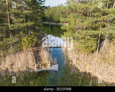 Vue aérienne d'un pont en bois reliant les lacs vert et blanc dans la réserve naturelle d'Antu avec une eau turquoise cristalline, Estonie. Banque D'Images