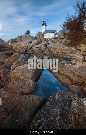 Vue du phare de Phare de Pontusval debout sur des rochers de granit avec un reflet d'eau sous un ciel bleu à Plouneour-Brignogan-plages, Bretagne, Fran Banque D'Images