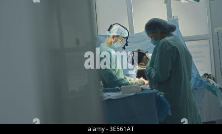 Chirurgie processus d'opération médication de traumatisme trois médecins avec infirmières assistants équipe coopérant dans la clinique hôpital d'urgence chirurgicale Banque D'Images