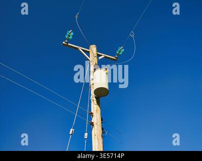 Yorkshire, Royaume-Uni - 17 mars 2026 : Un poteau électrique en bois et des lignes électriques s'élèvent dans un ciel bleu éclatant dans le Yorkshire rural, Royaume-Uni, par une journée ensoleillée, créant une vue d'infrastructure moderne et propre Banque D'Images