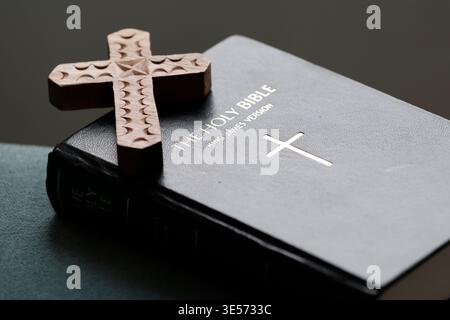 Croix décorative en bois sculptée à la main sur une couverture en cuir noir Holy Bible. Banque D'Images