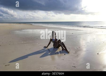 Jeune femme assise sur la plage de Bofa, Kilifi, Kenya Banque D'Images