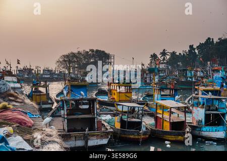 Des bateaux de pêche colorés ont accosté dans un port indien au lever du soleil, créant une scène pittoresque. L'eau tranquille reflète les teintes vibrantes, tandis que PA Banque D'Images