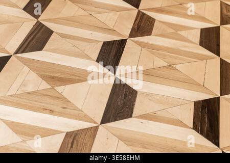 Photographie rapprochée de parquet géométrique avec panneaux triangulaires incrustés avec alternance de tons de bois clairs et sombres et de grain visible Banque D'Images
